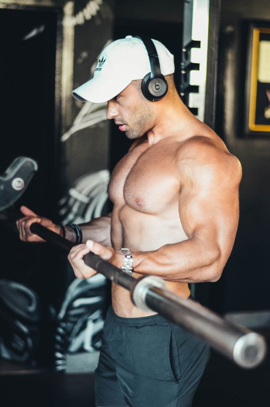 Hombre haciendo pesas con barra en gimnasio después de tomar ganador de masa muscular